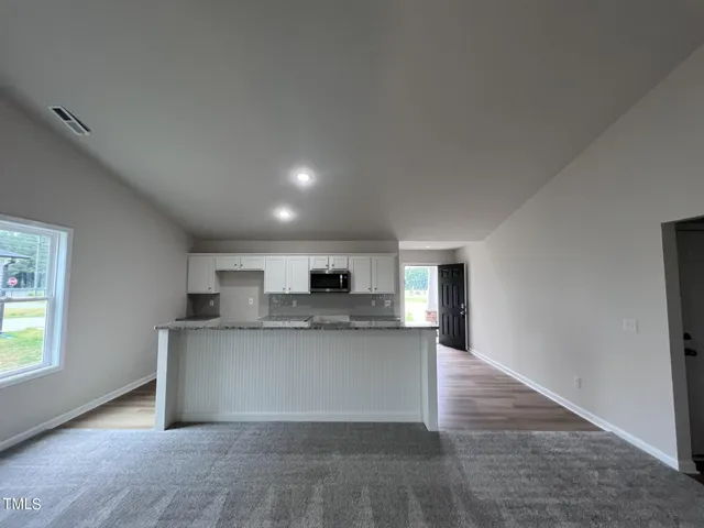 a view of kitchen with kitchen island a sink wooden floor and a refrigerator