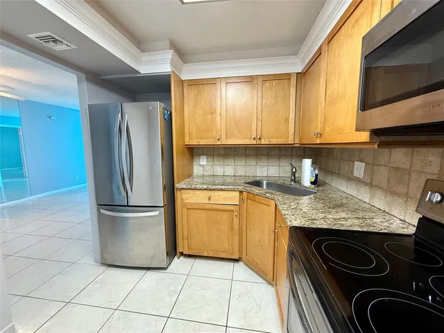 a kitchen with granite countertop a refrigerator and a stove top oven