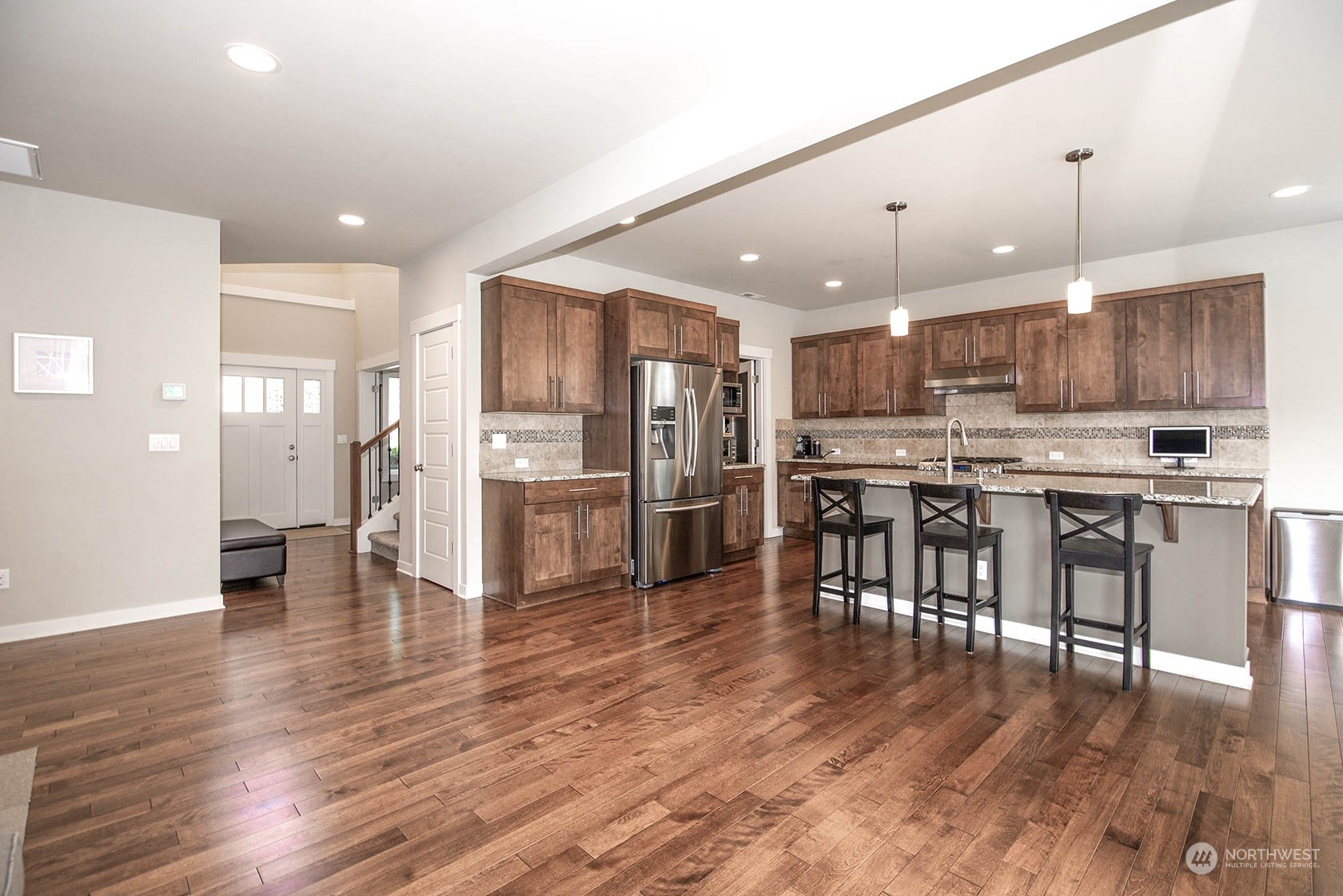 21127 35th Drive Southeast Bothell, WA 98021 - Photo 10 of 40 a kitchen with stainless steel appliances kitchen island granite countertop a refrigerator a stove a sink a dining table and chairs with wooden floor