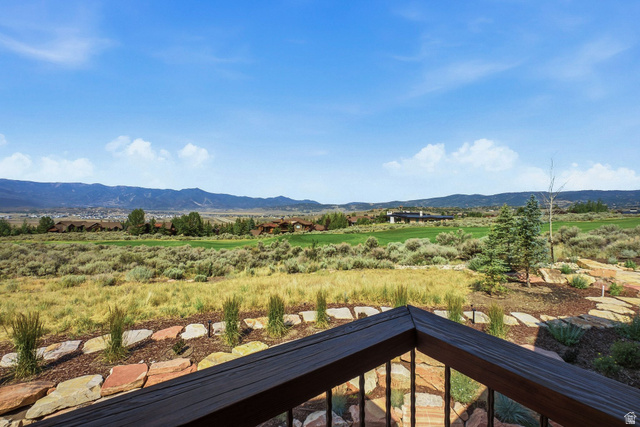 7885 North Rabbitbrush Court, Unit 13 Park City, UT 84098 - Photo 72 of 88 Expansive outdoor living area featuring a dark wood railing, stone hardscaping, and natural landscaping with mature trees