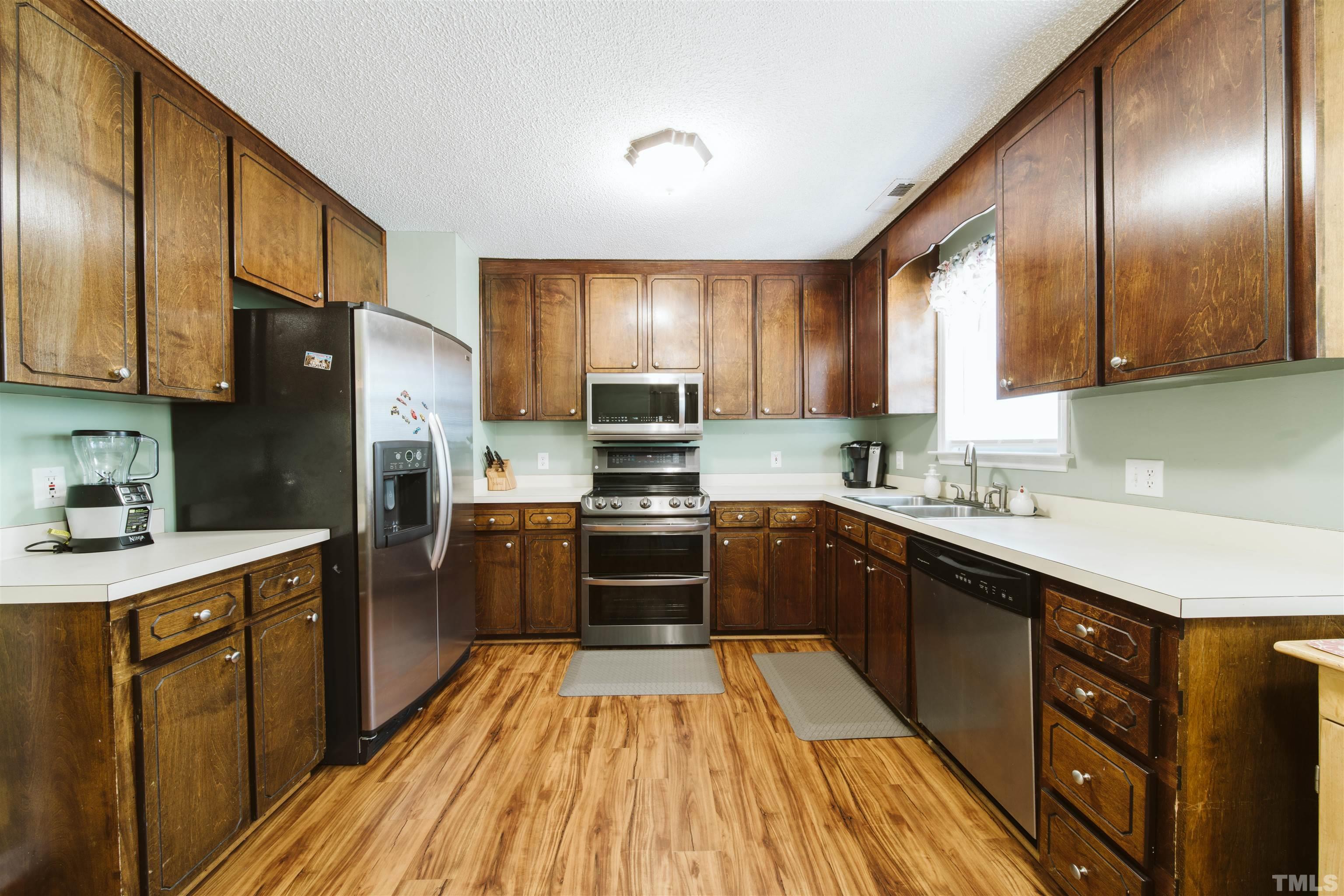 1283 Lee Road Clayton, NC 27520 - Photo 13 of 32 a kitchen with stainless steel appliances granite countertop wooden cabinets a stove top oven a sink and dishwasher
