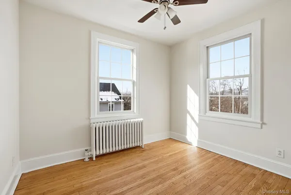 an empty room with wooden floor fan and windows
