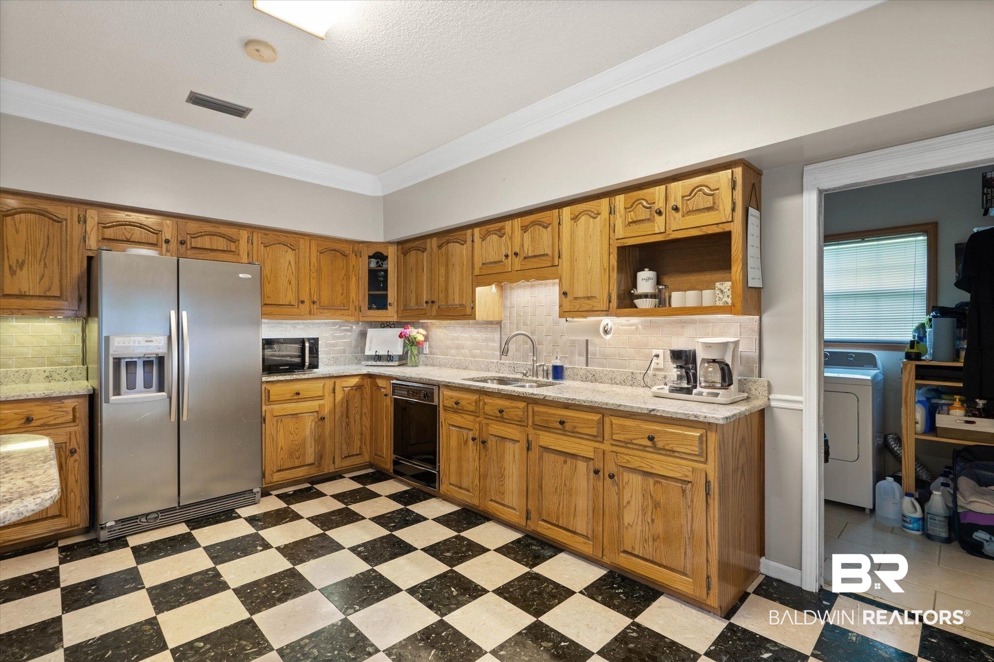 2300 Radcliff Road Saraland, AL 36571 - Photo 7 of 56 Kitchen with black appliances, washer / clothes dryer, light floors, crown molding, and tasteful backsplash