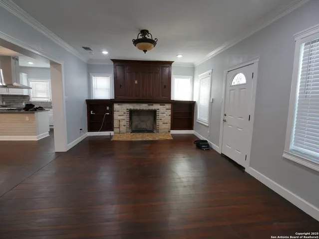 an empty room with wooden floor a fireplace and windows