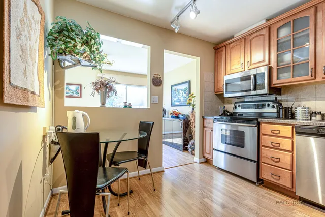 a kitchen with stainless steel appliances granite countertop a stove top oven a sink dishwasher a dining table and chairs with wooden floor