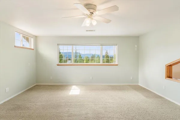 an empty room with windows and fan