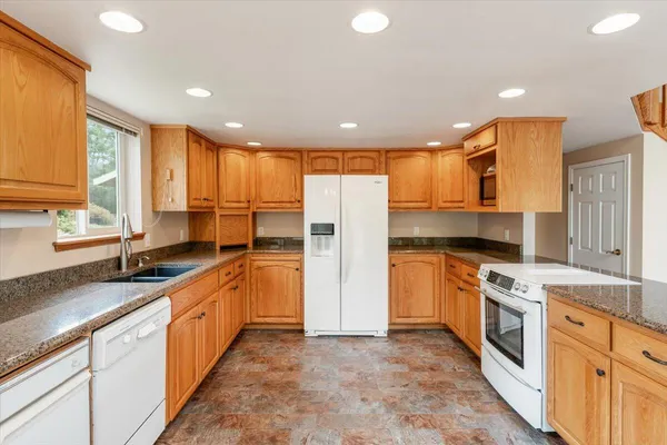 a kitchen with stainless steel appliances granite countertop a stove a sink and a refrigerator