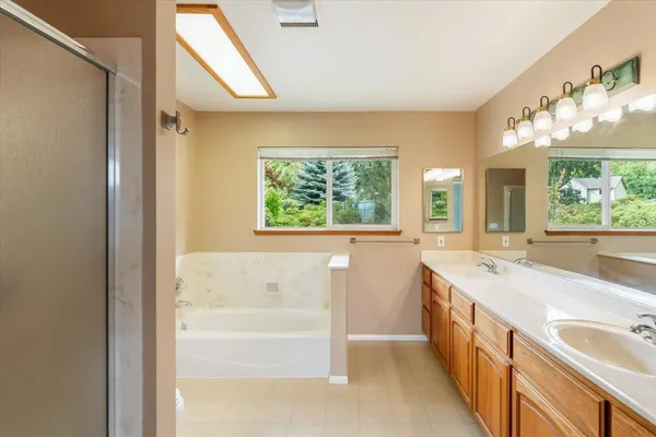 a spacious bathroom with a tub sink and mirror