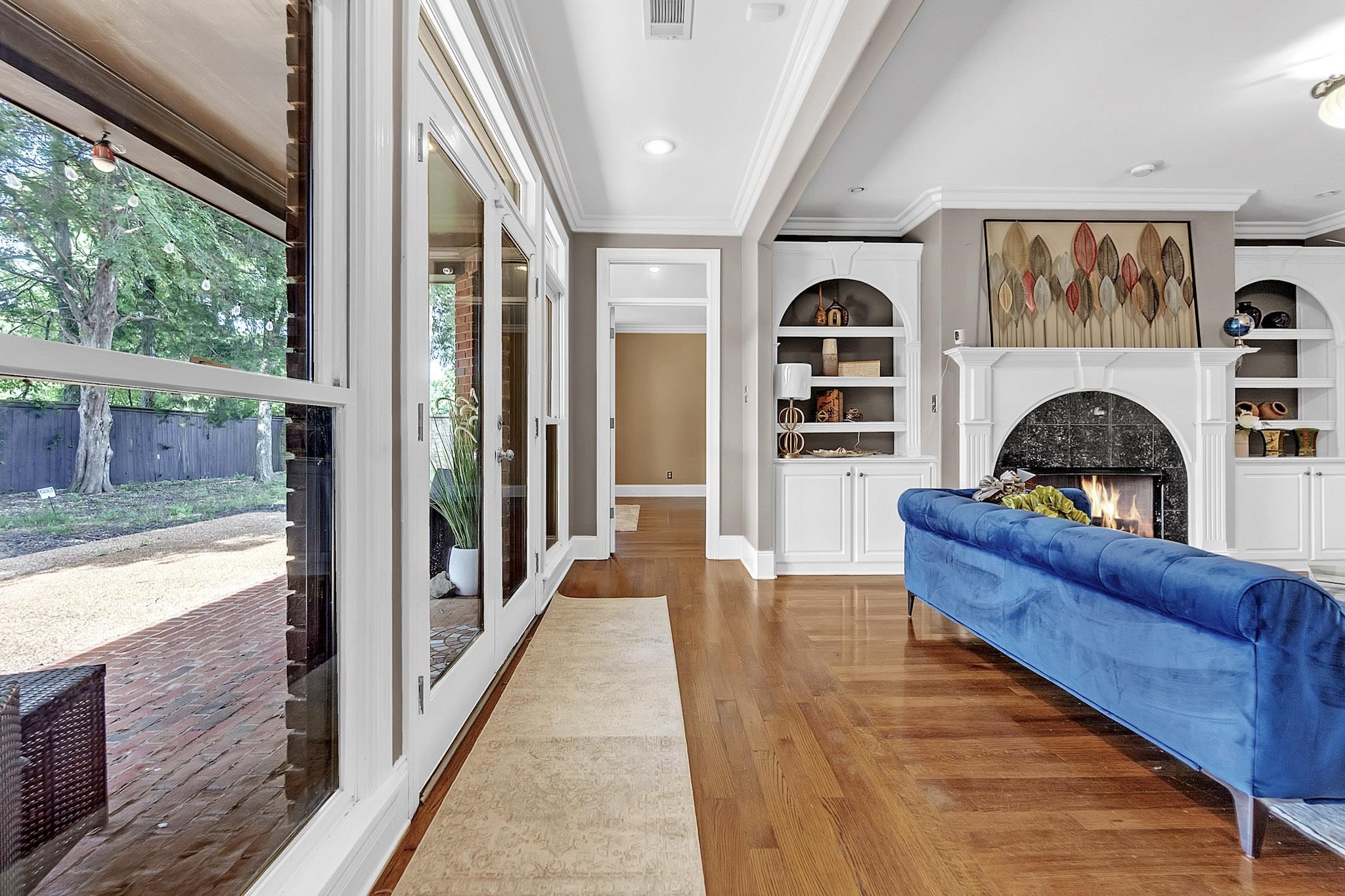 649 Ridge Springs Road Collierville, TN 38017 - Photo 21 of 38 Living space featuring wood-finish flooring, a fireplace with a dark stone surround, and built-in white cabinetry with arched shelving