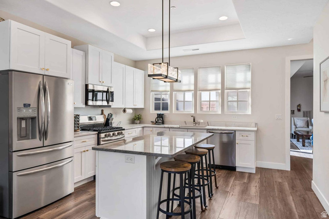 4311 Canterbury Road, Unit F2 Hurricane, UT 84737 - Photo 2 of 18 Kitchen featuring white cabinetry, stainless steel appliances, a center island with countertop seating, and wood-finish flooring