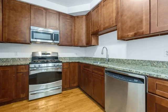 a kitchen with granite countertop wooden cabinets stainless steel appliances and a counter space