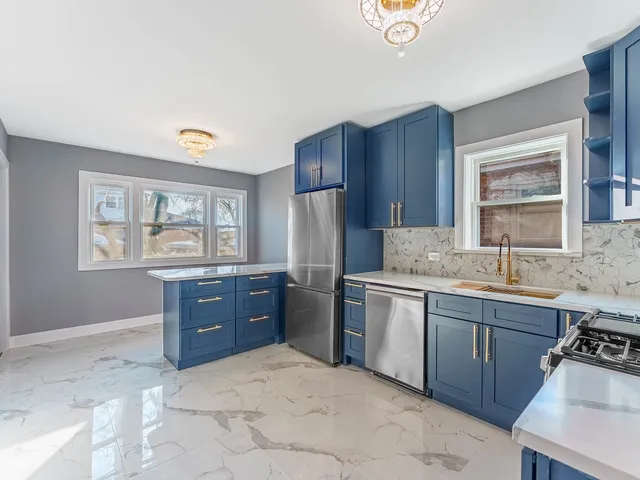 a kitchen with stainless steel appliances granite countertop a stove a sink dishwasher and a refrigerator with wooden cabinets