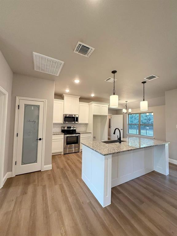 1015 Bluestem Weatherford, TX 76087 - Photo 3 of 11 a open kitchen with kitchen island white cabinets and stainless steel appliances