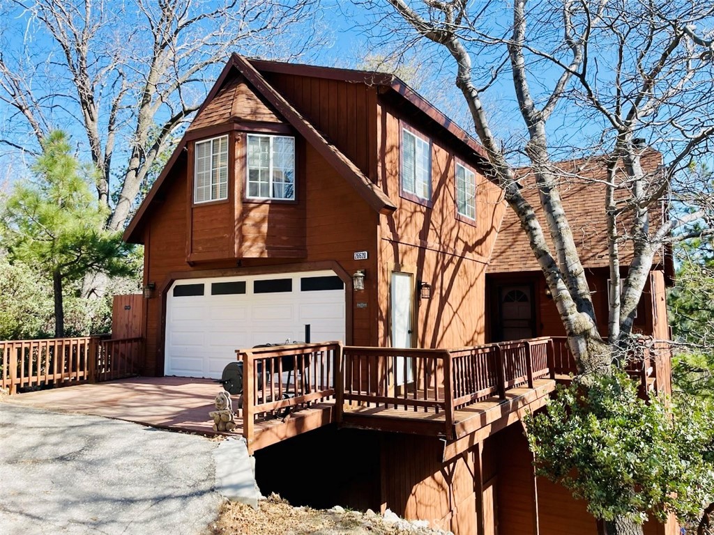 a view of a house with wooden fence and a large tree