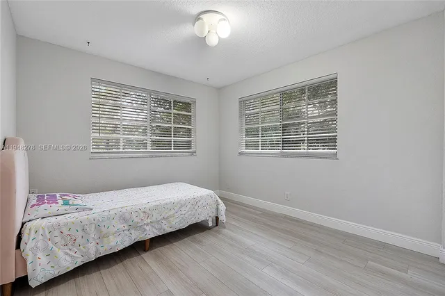 a bedroom with a bed lamp and wooden floor