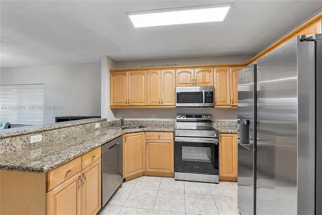 a kitchen with stainless steel appliances granite countertop a refrigerator and a stove top oven