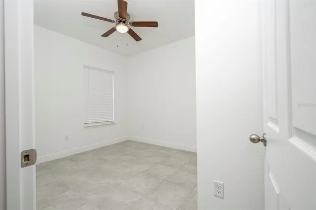 an empty room with a window and a ceiling fan