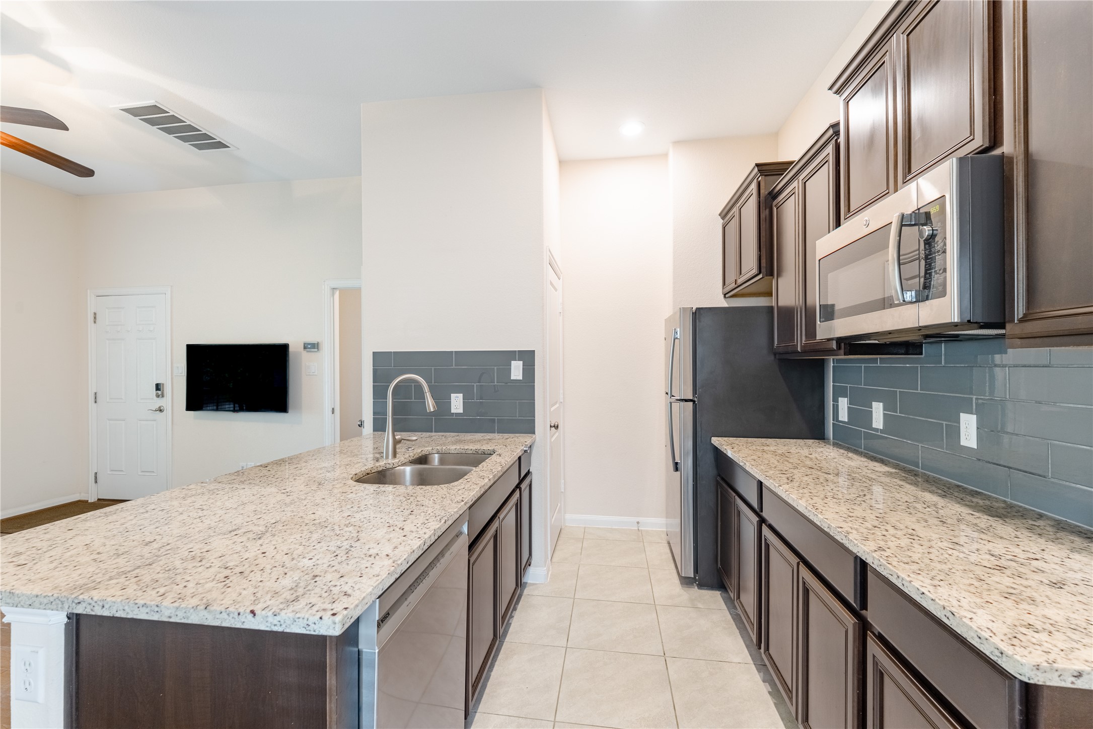 5012 Yucca Bloom Drive Georgetown, TX 78626 - Photo 17 of 35 Multi-Gen Kitchen featuring granite countertops, dark wood-finish cabinetry, stainless steel appliances, and a subway tile backsplash