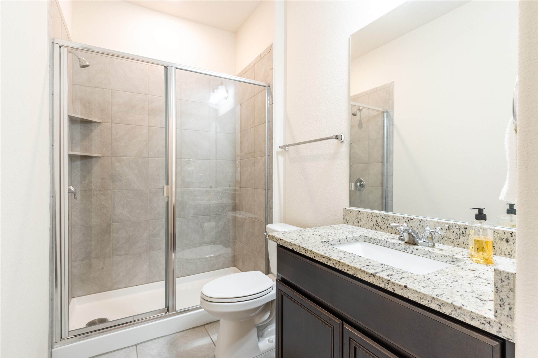 5012 Yucca Bloom Drive Georgetown, TX 78626 - Photo 18 of 35 Shower with sliding glass enclosure featuring built-in shelving, stone-finish tile surround, and chrome fixtures