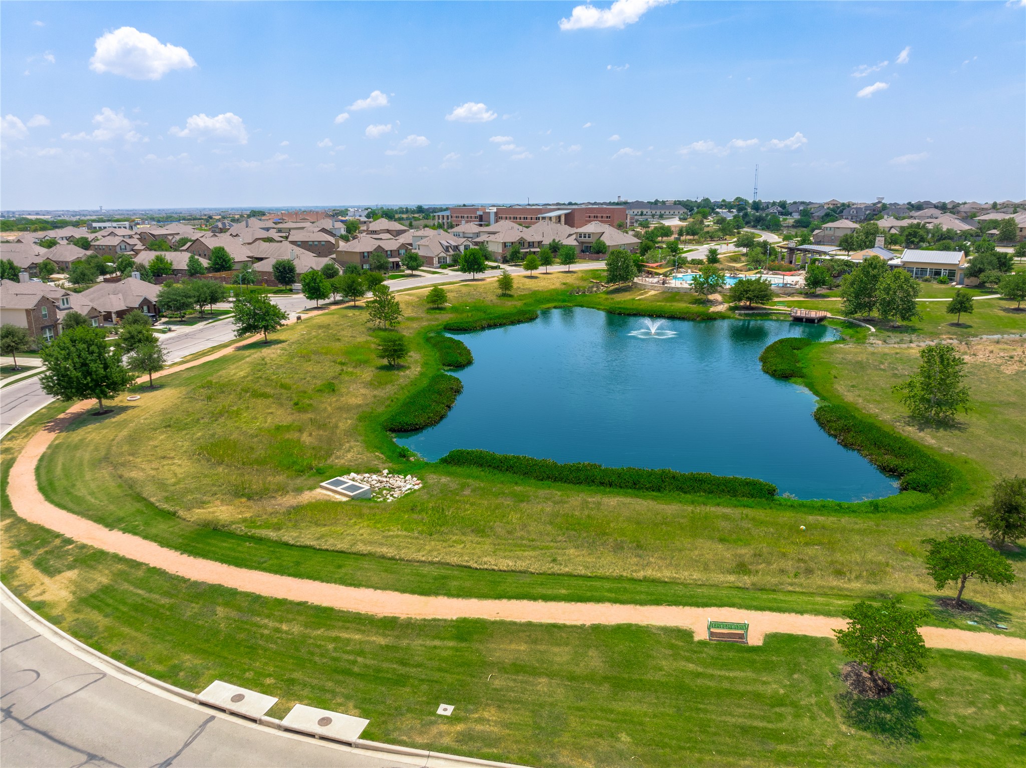 5012 Yucca Bloom Drive Georgetown, TX 78626 - Photo 33 of 35 Community pond with aerating fountain, surrounded by a paved walking path, green spaces, and mature trees