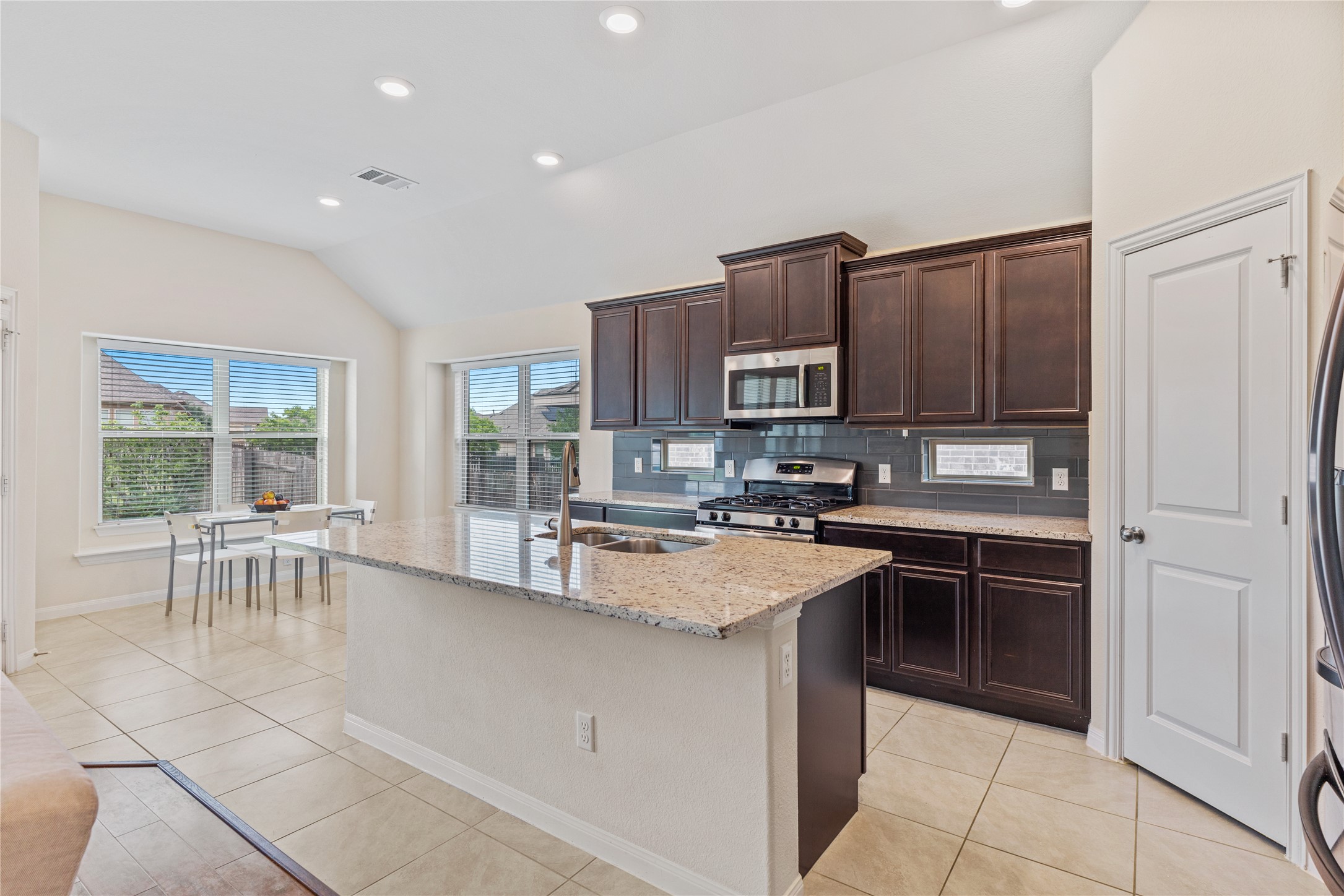 5012 Yucca Bloom Drive Georgetown, TX 78626 - Photo 7 of 35 Kitchen featuring an island with stone countertops, dark wood cabinetry, stainless steel appliances, tile flooring, and recessed lighting