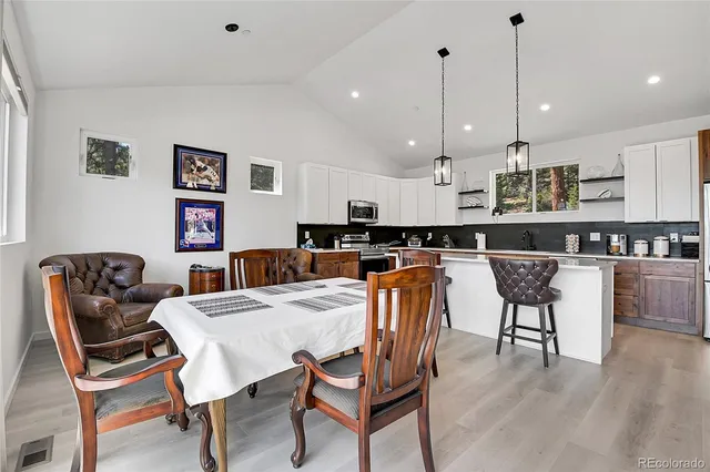 a kitchen with stainless steel appliances granite countertop a refrigerator a stove a sink a dining table and chairs with wooden floor