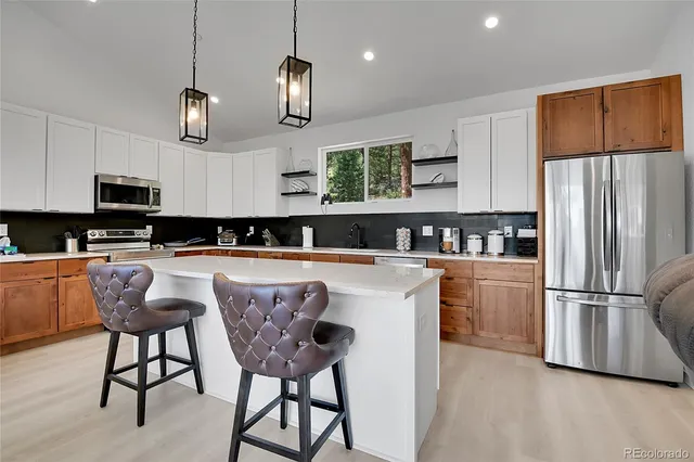 a kitchen with stainless steel appliances granite countertop a kitchen island a stove a table and chairs in it