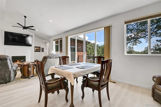 a kitchen with stainless steel appliances granite countertop a refrigerator a stove a sink a dining table and chairs with wooden floor