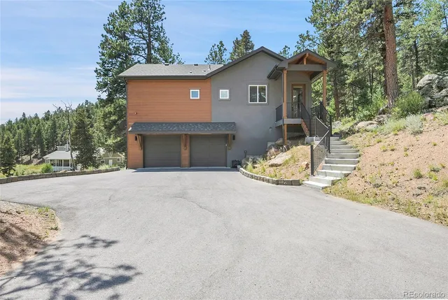 a front view of a house with a yard covered with snow and trees