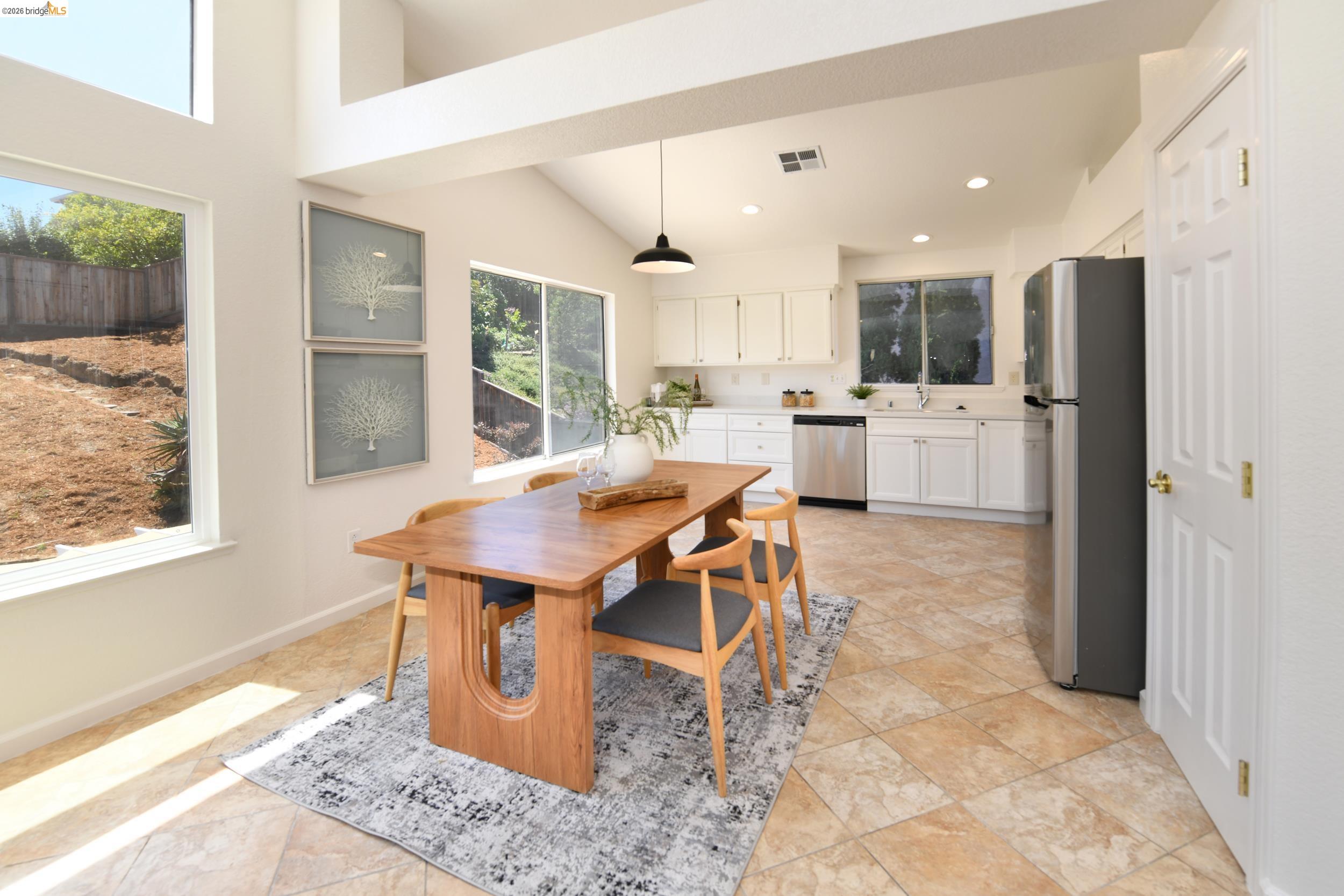 512 Burdick Drive Bay Point, CA 94565 - Photo 18 of 50 Open-concept kitchen and dining area featuring vaulted ceilings, ample natural light from multiple windows, white cabinetry, stainless steel appliances, and tiled flooring
