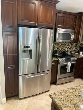 a metallic refrigerator freezer sitting in a kitchen