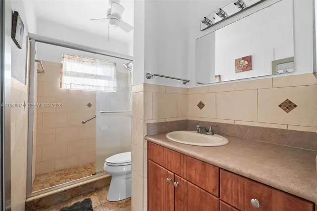 a bathroom with a granite countertop sink a toilet a shower and a mirror