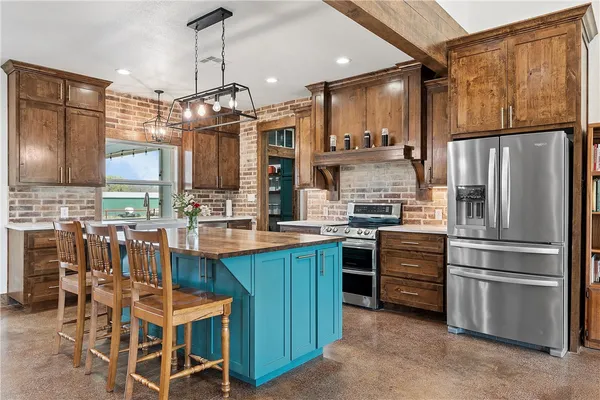 a kitchen with stainless steel appliances a refrigerator a stove a sink and chairs