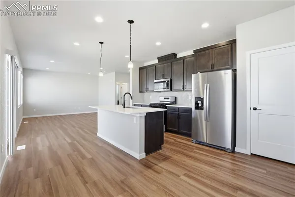 a kitchen with kitchen island a refrigerator a sink and wooden floor