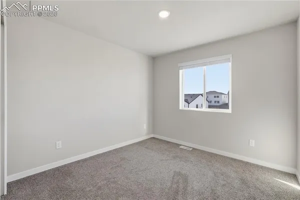 a view of an empty room with closet and a window