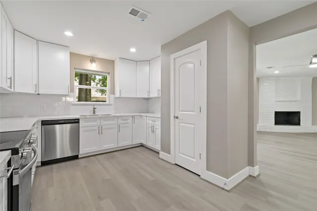 a kitchen with white cabinets and sink