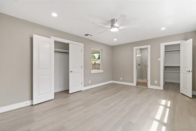 an empty room with wooden floor closet and windows
