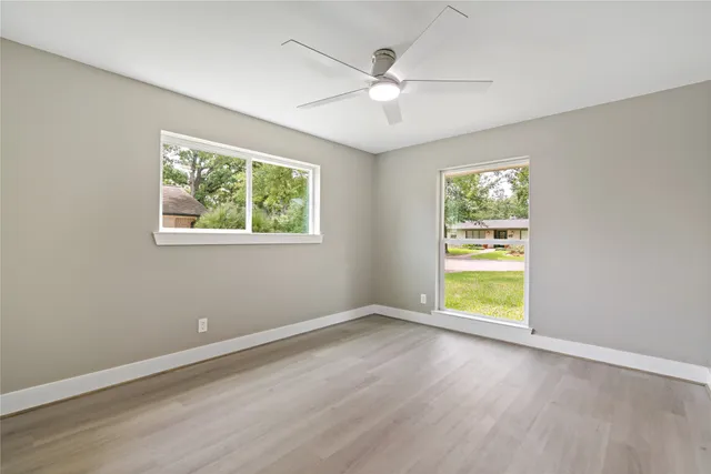 a view of an empty room with a window and wooden floor