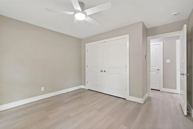 an empty room with wooden floor and ceiling fan