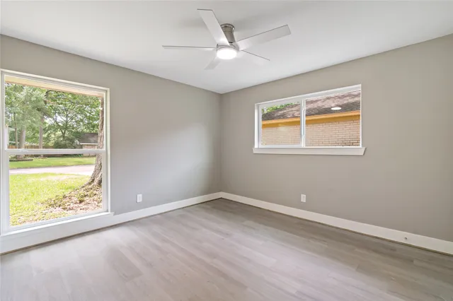 an empty room with wooden floor and windows