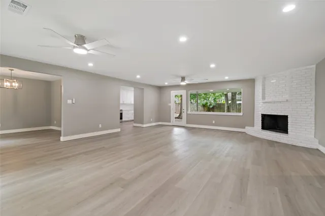 an empty room with windows fireplace and wooden floor