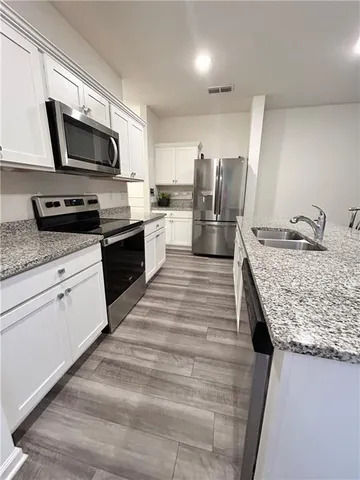 a kitchen with granite countertop kitchen island wooden cabinets a counter top space stainless steel appliances and a window