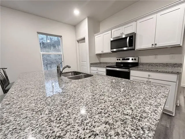 a kitchen with granite countertop a stove a sink and a microwave