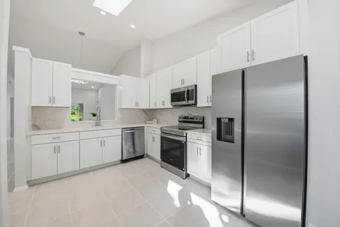 a kitchen with a refrigerator a sink stainless steel appliances and cabinets