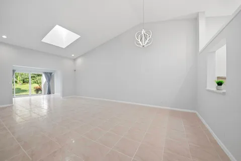 an empty room with kitchen view and wooden floor