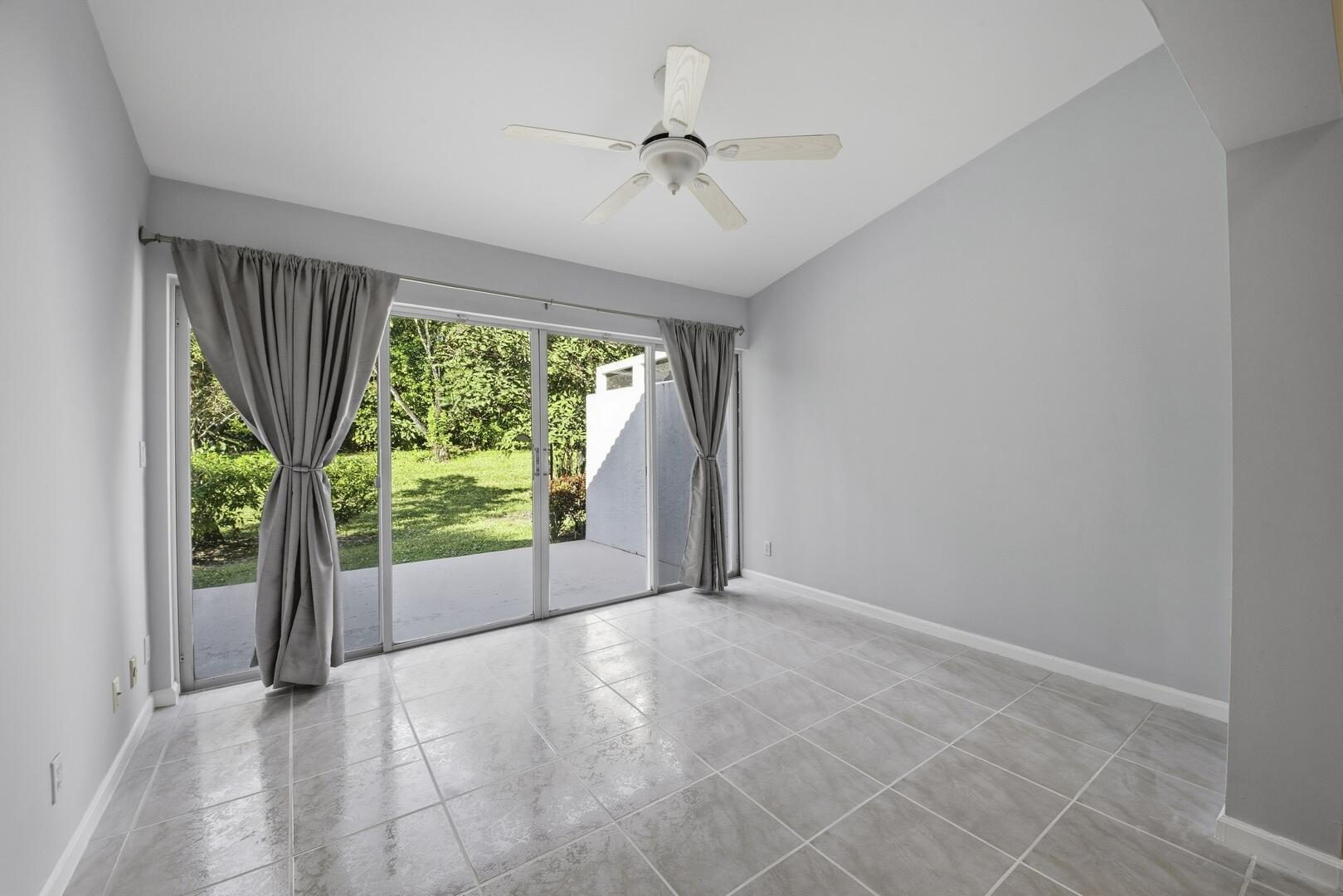 7617 Island Breeze Terrace Boynton Beach, FL 33437 - Photo 32 of 46 an empty room with floor to ceiling windows and a ceiling fan