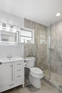 a bathroom with a toilet a sink a mirror and a shower