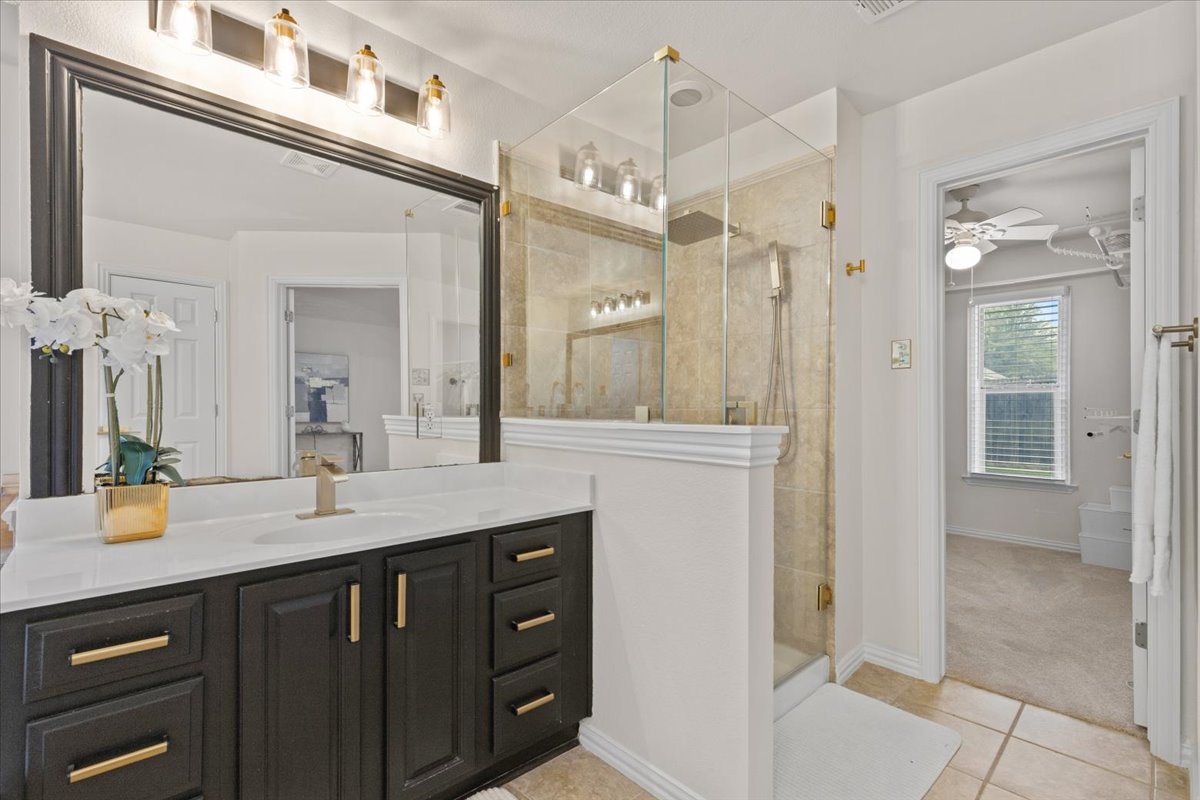 2501 Aspen Meadow Road Leander, TX 78641 - Photo 18 of 30 Modern bathroom featuring a dark wood-finish vanity with gold-tone hardware, white countertop, and a rectangular undermount sink