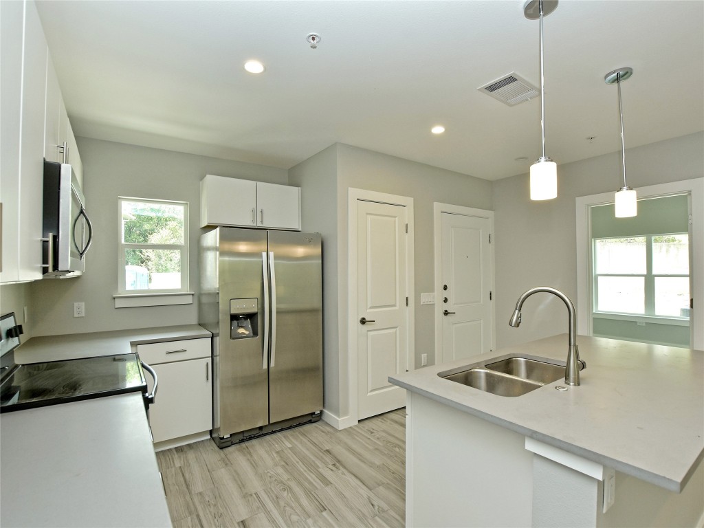 a kitchen with granite countertop a sink a counter space appliances and cabinets