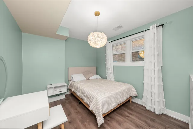 a bedroom with a bed chandelier and a window